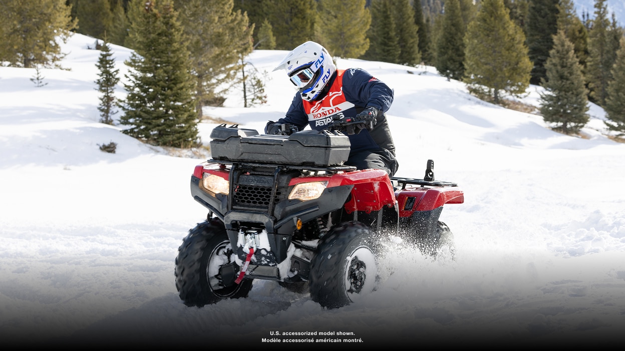 Person riding an ATV through snow