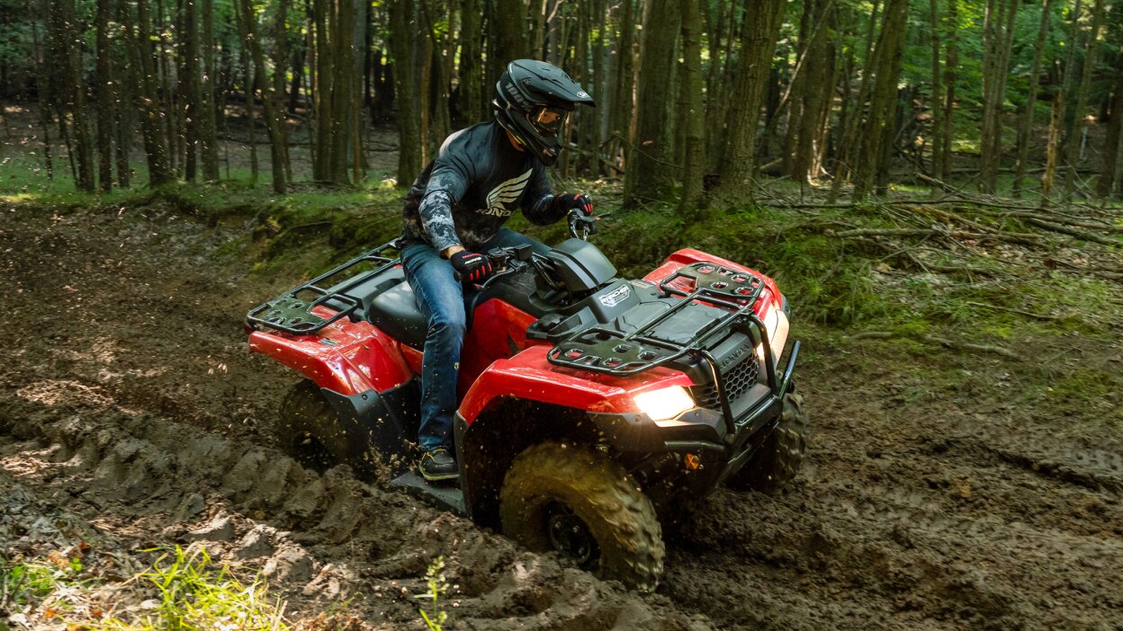 Driver on Rancher, making right turn on dirt road. Wood landscape in background.