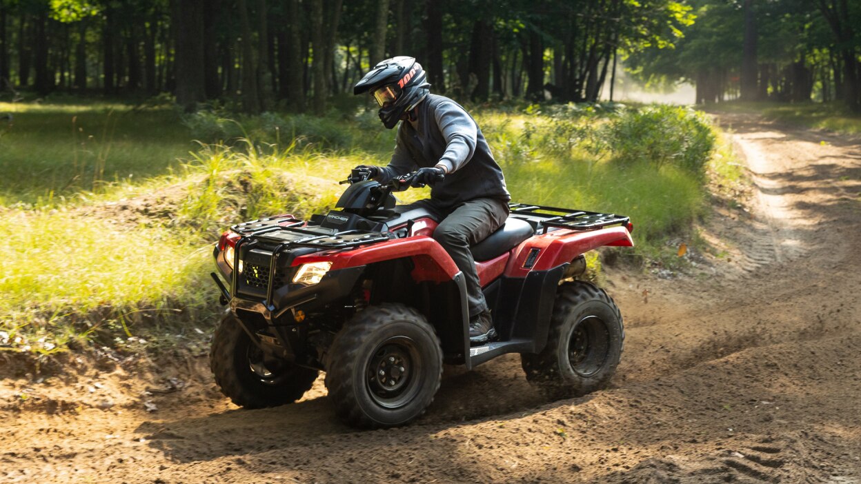Driver on Rancher turning right on dirt road. Grass and wood landscape in the background.