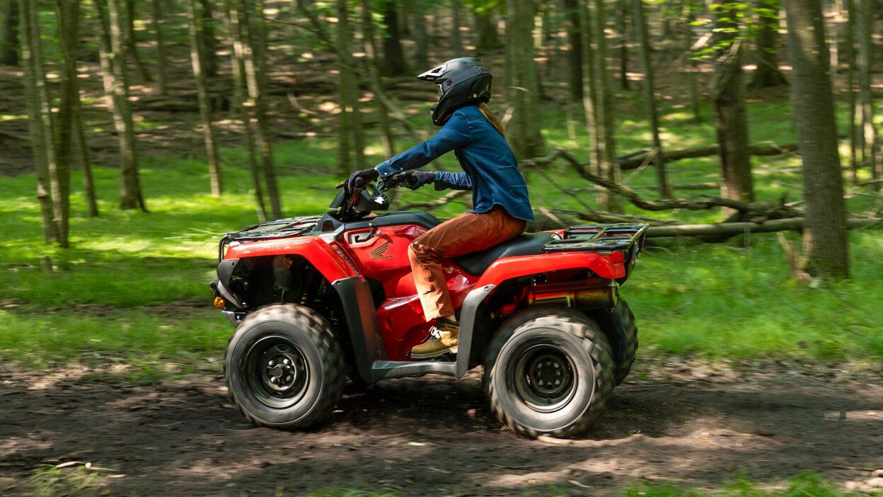 Left angle of a Driver on Rancher going left on dirt road. Wood landscape in background.