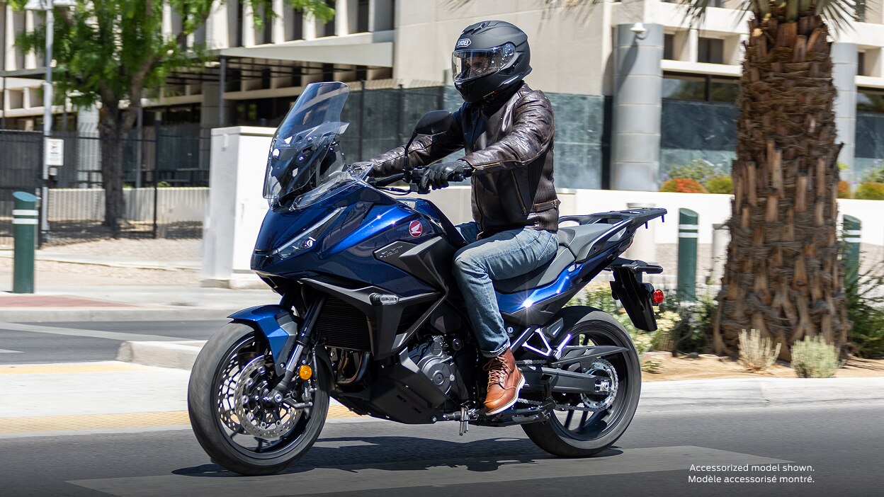 Rider facing left on NT1100. City landscape in background.