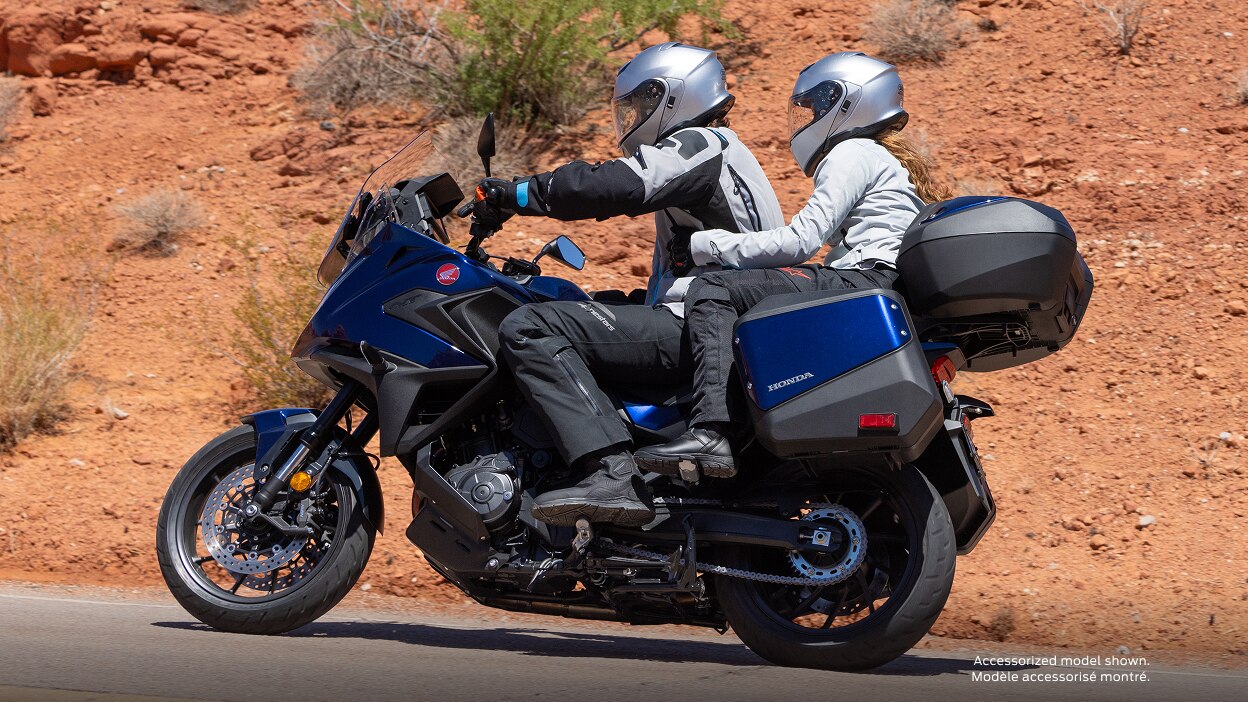 Rider and passenger facing left on NT1100. Desert landscape in background.