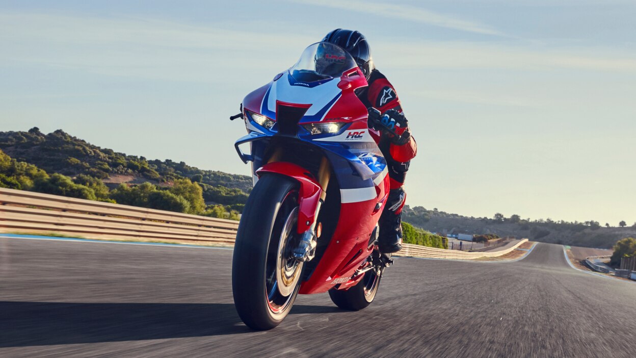 Rider on CBR1000RR-R FIREBLADE SP going left on track. Sunlight in background.