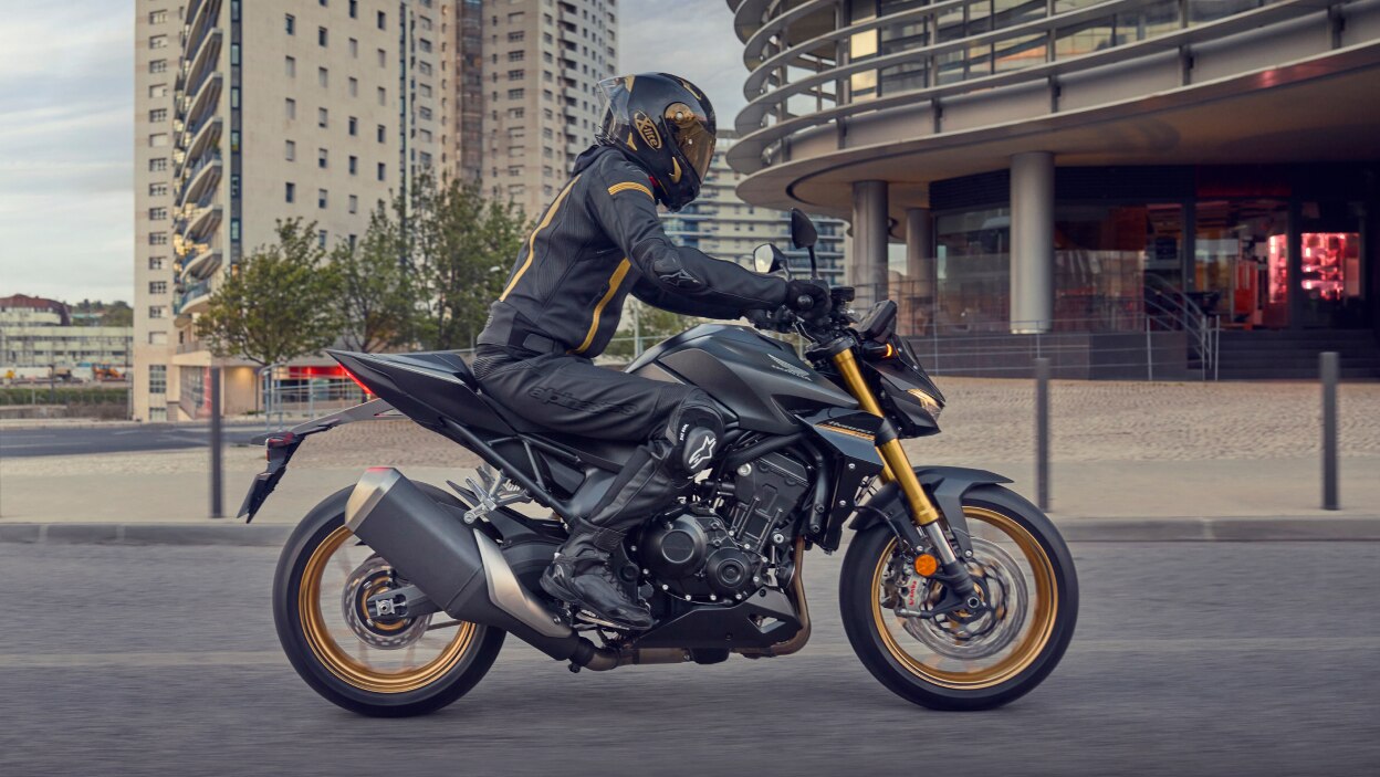 Rider going right on CB1000SP in city landscape.