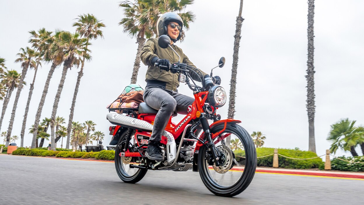 Person on red Trail 125 going right on road. Palm trees in background.