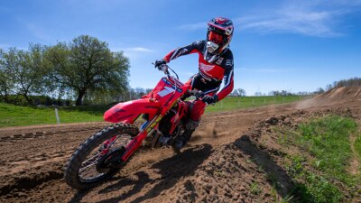 Motocross rider riding a red Honda dirt bike on a dirt track