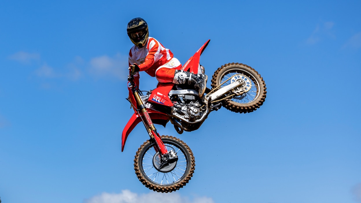 Rider mid air on motorbike. Blue sky in background.