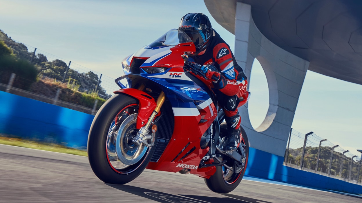 Rider on CBR1000RR-R Fireblade on race track. Bridge in background.