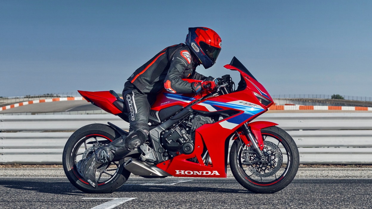 Rider on CBR1000RR-R Fireblade on race track. Blue sky in background.