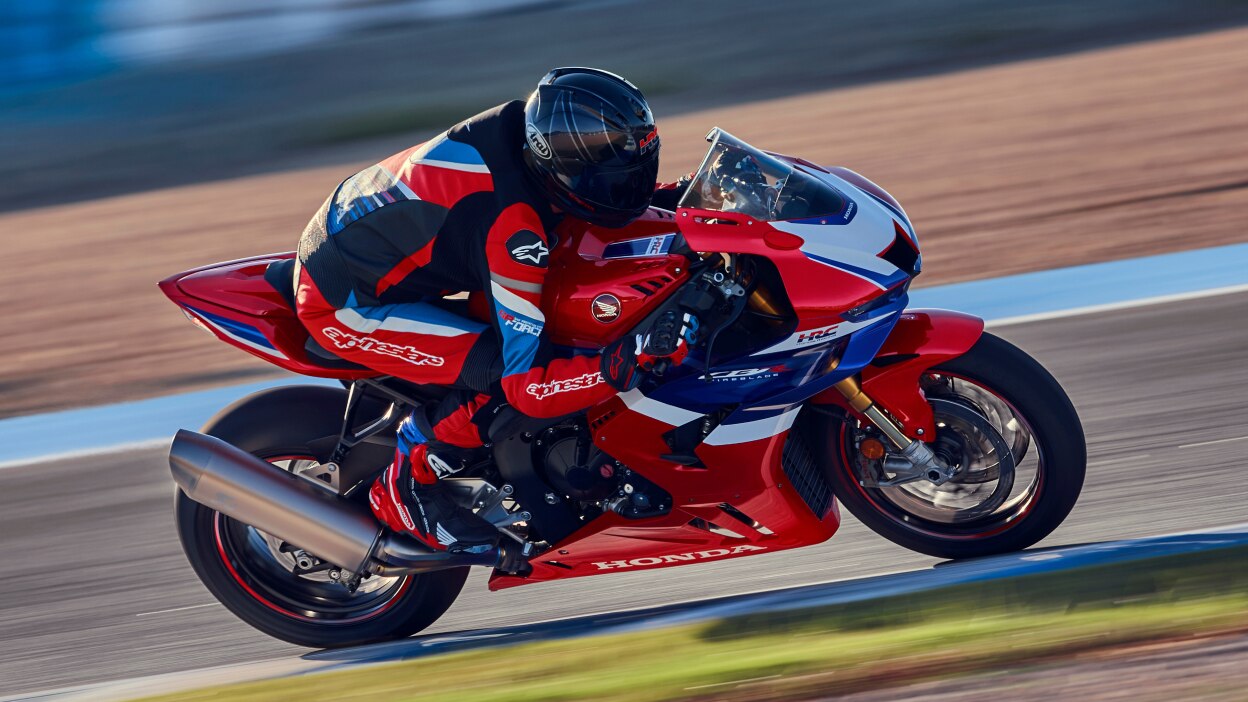 Rider on CBR1000RR-R Fireblade on race track. Blue sky in background.