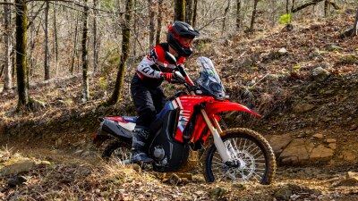 Rider on CRF450L going downhill on dirt track.