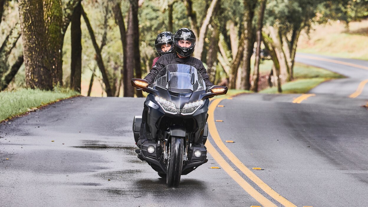 A touring motorcycle riding along a coastal road.