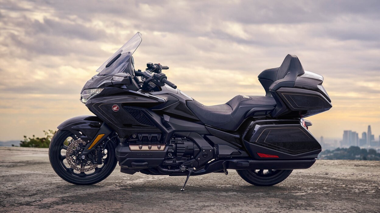 Side profile of a touring motorcycle parked against a scenic landscape.