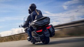 A motorcyclist leaning into a sharp curve on a mountain road.