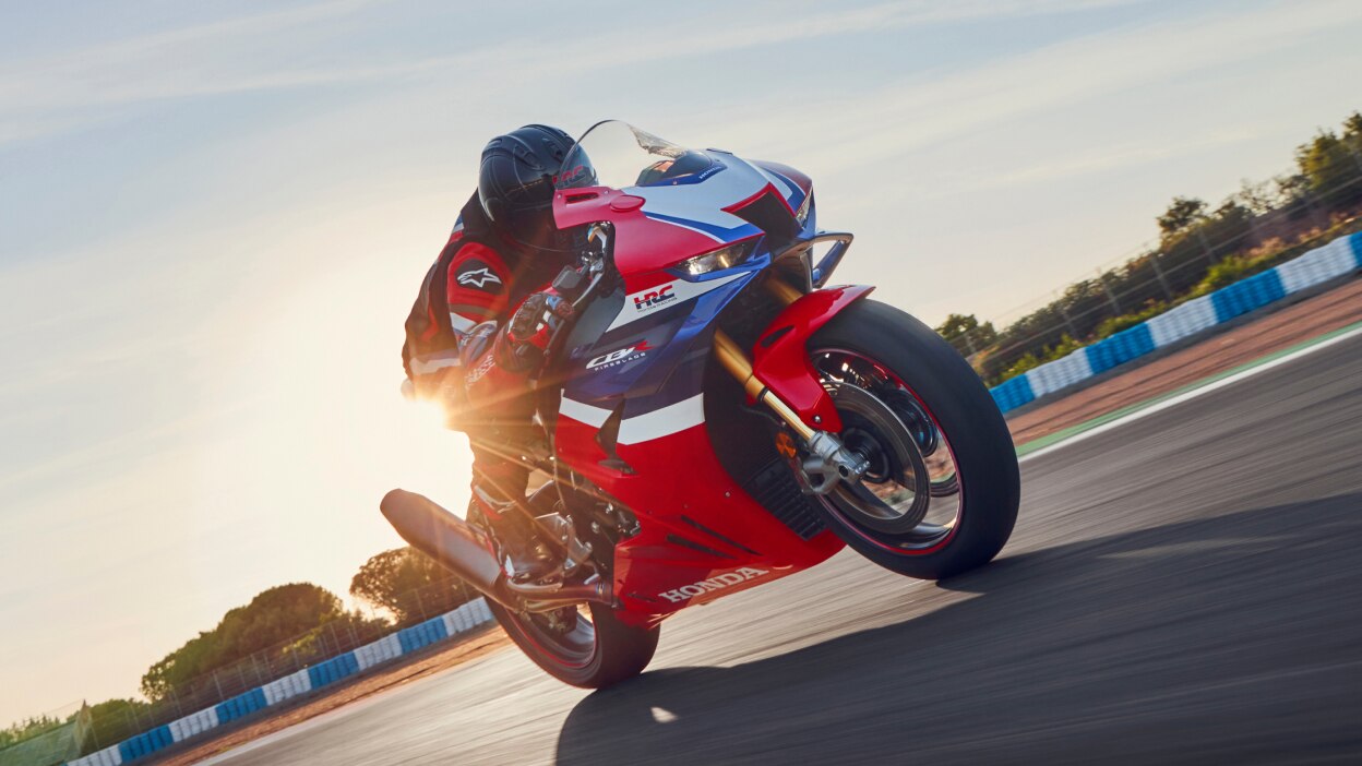 Rider on CBR1000RR-R Fireblade on race track. Blue sky in background.