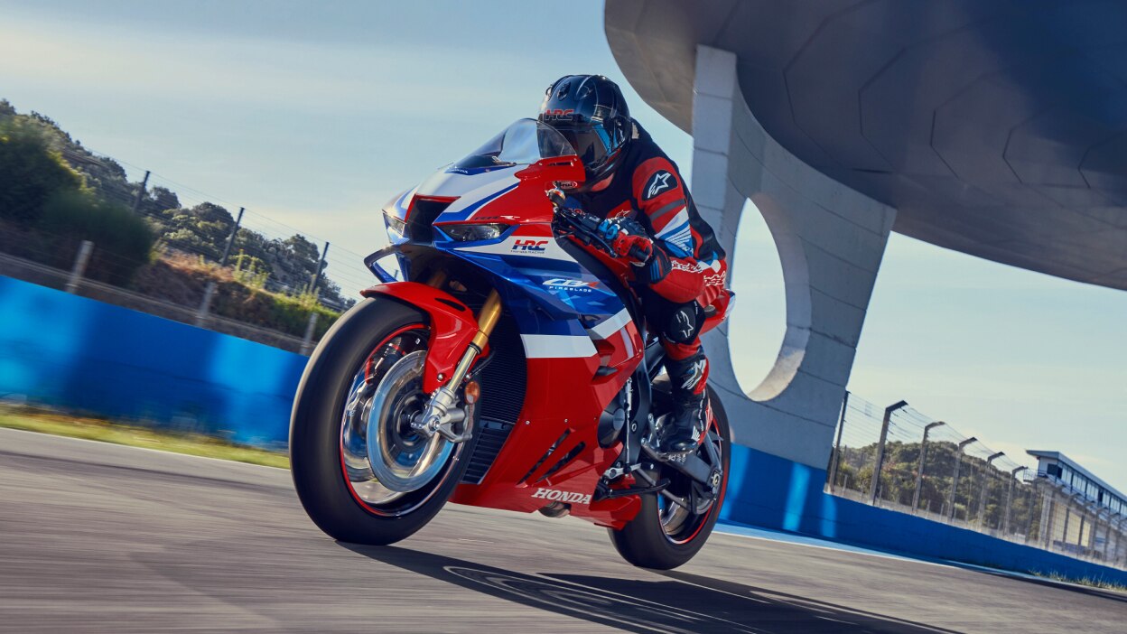 Rider on CBR1000RR-R Fireblade on race track. Bridge in background overhead.