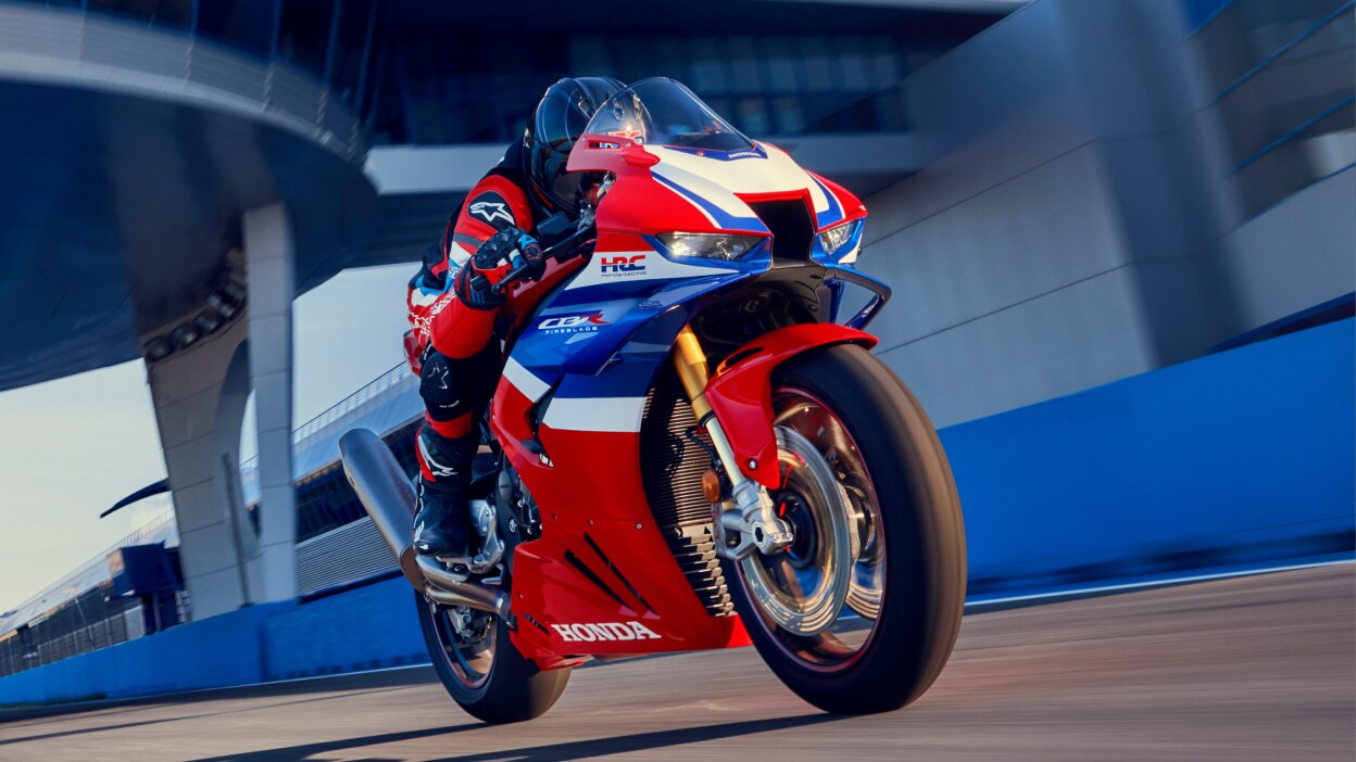 Rider on CBR1000RR-R Fireblade on race track. Bridge in background overhead.