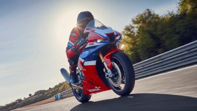 Rider on CBR1000RR-R Fireblade on race track. Blue sky in background.