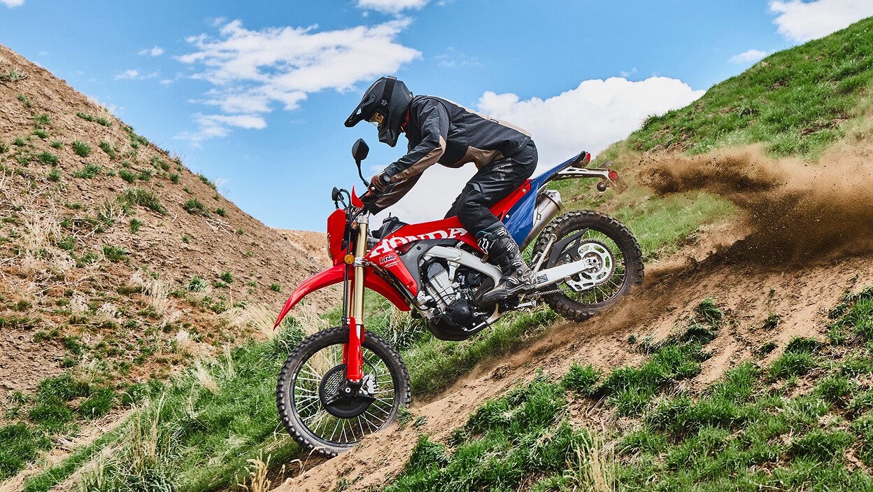 A rider on a dual sport motorcycle on a grassy hill.