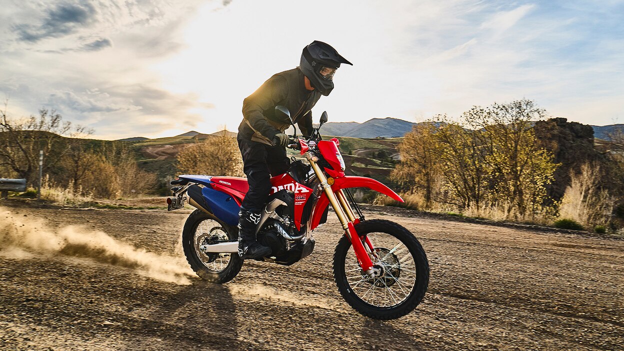 A rider on a dual sport motorcycle on a dirt trail.