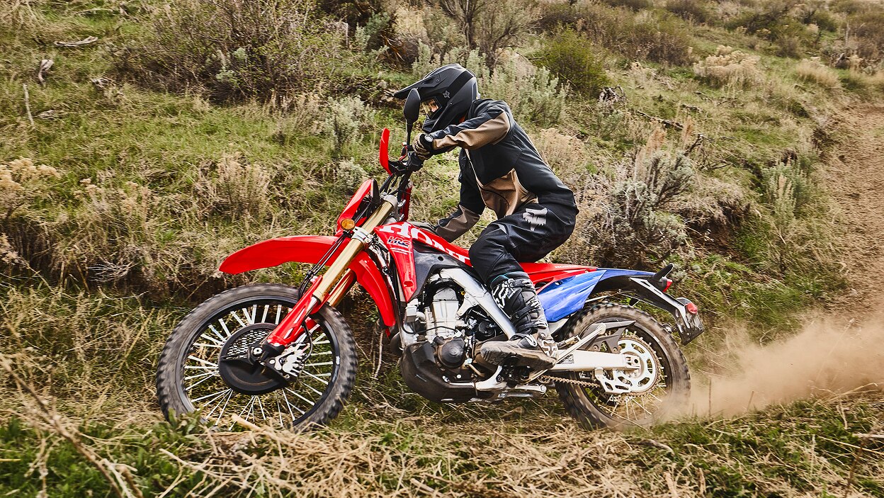 A rider on a dual sport motorcycle kicking up dirt on a trail.