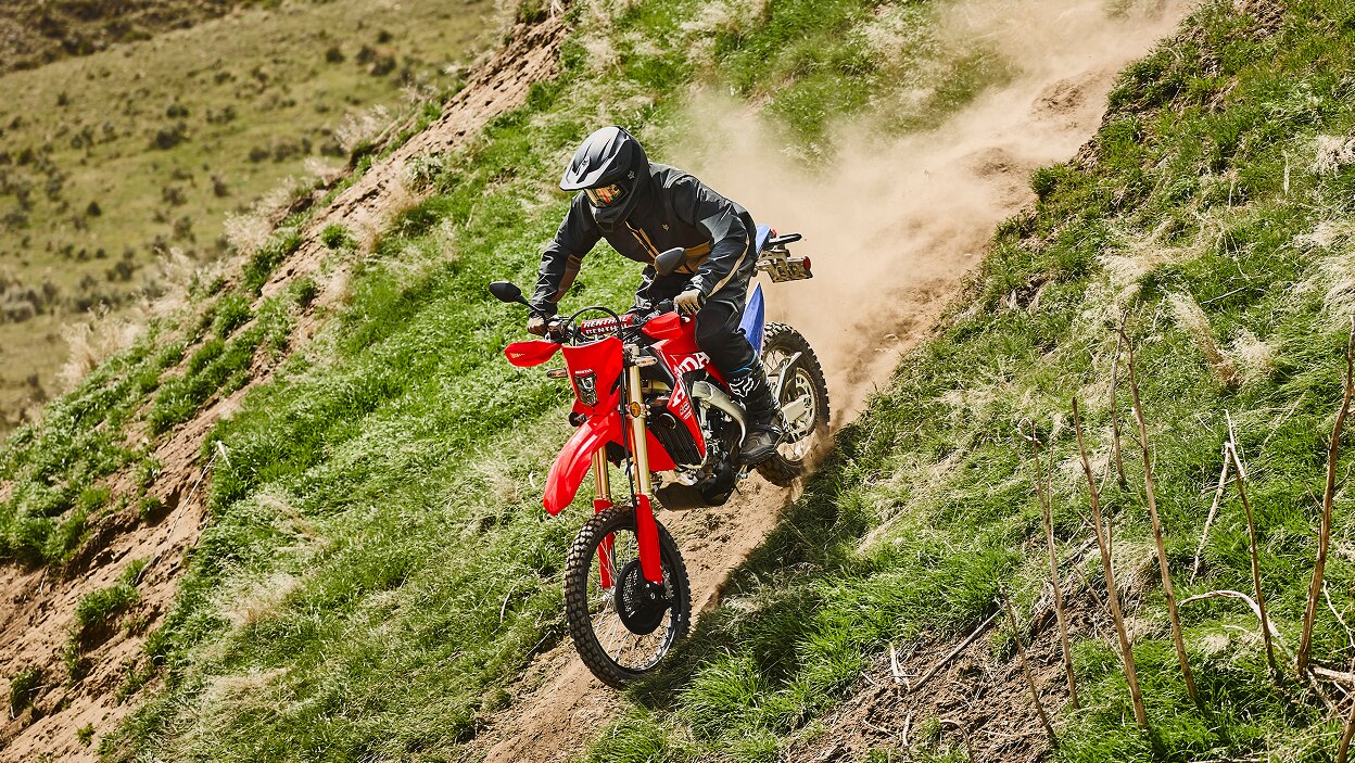 A rider on a dual sport motorcycle in an off-road setting.