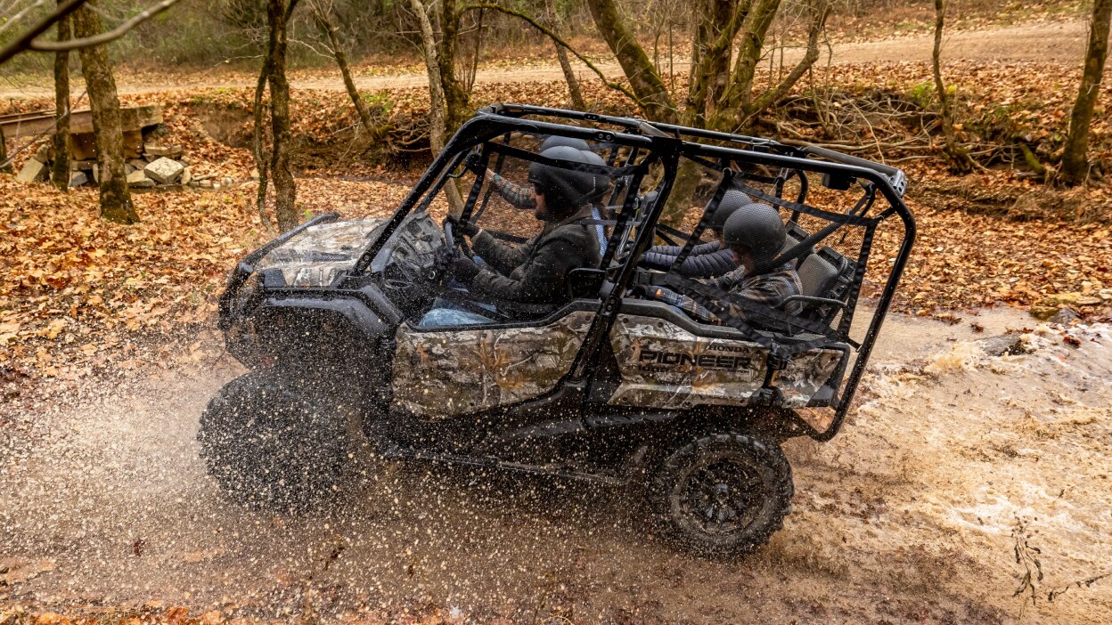 Four people in sxs halfway into muddy water.