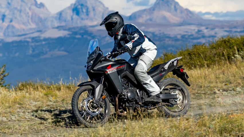 a rider on a Honda Transalp motorcycle with mountains in the background